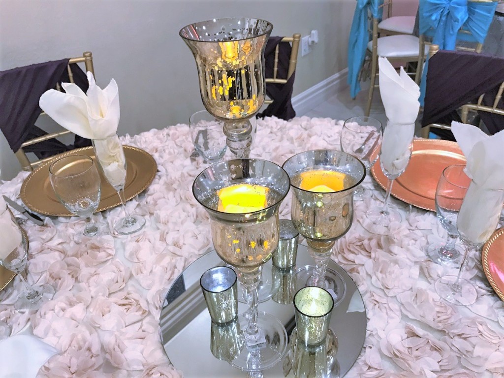 Reception table styled with gold accents, greenery and candlelight